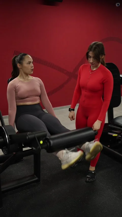 Trainer motivates client during leg extension set Stock Footage 337956889