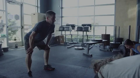 Trainer observes trainees practicing exercises in small gym space Stock Footage 312701614