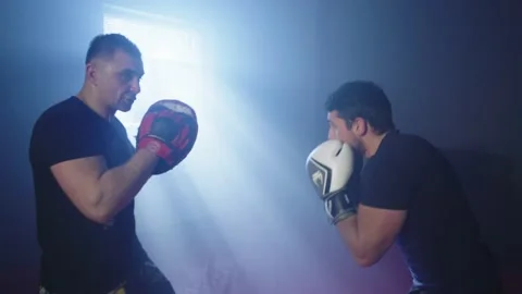 A trainer practices punches and trains with a boxer. Stock Footage 236900780