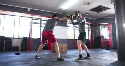 Trainer shifting focus mitts to prompt indian trainee punching with boxing Stock Footage 344850247
