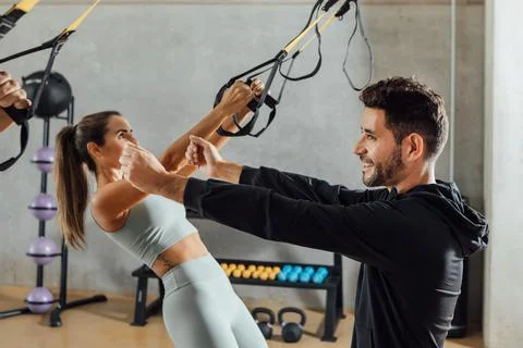 Trainer showing right position to do the suspension training exercise to client. Stock Photos