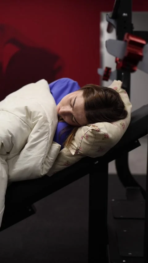 Trainer sleeps on gym machine after long workdaym Stock Footage 328253811