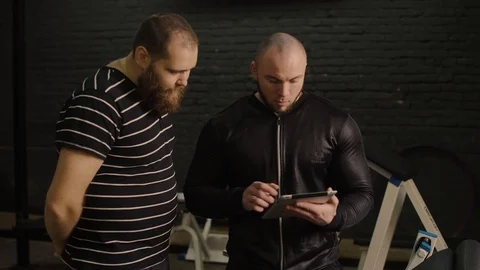 Trainer with tablet in hands work with fat man in the gym Vídeo Stock 87916539