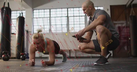 Trainer tapping phone and timing fitness plank, woman making small shifts while Stock Footage 331789713