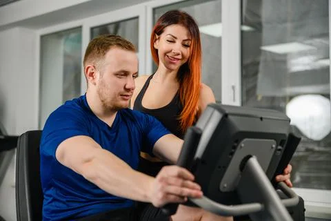 Trainer teach woman to use gym equipment Stock Photos