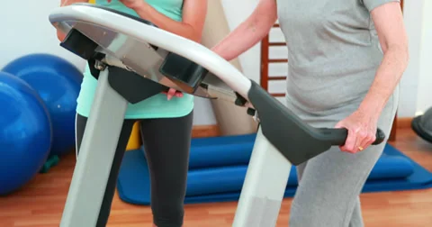 Trainer watching elderly client using treadmill Stock Footage 34253878