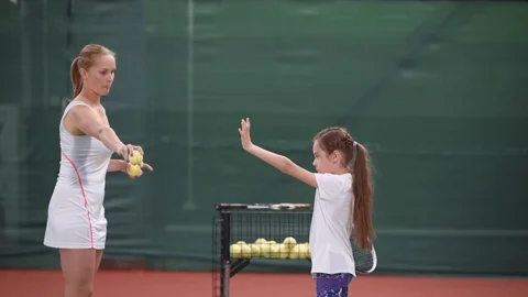Trainer woman and little girl exercising hit with racket on tennis court Stock Footage