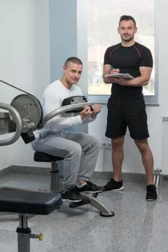 Trainer Writing On Clipboard While Man Training Back Stock Photos