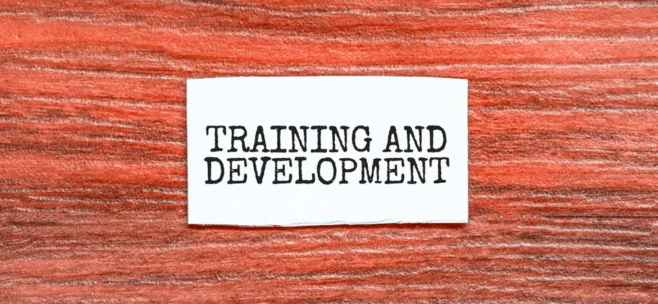 TRAINING AND DEVELOPMENT text on the piece of paper on the red wood backgroun Stock Photos