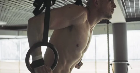 Training with gymnastic rings, strength exercise in closed gym. Men doing Stock-Footage 129980461