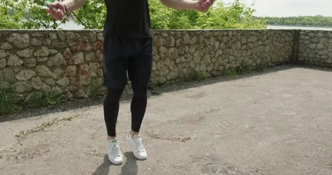 Training with jump rope, intense strength exercise outdoor. Men doing difficult Stock Footage 132778620