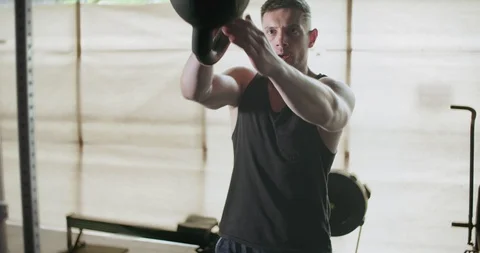 Training with kettlebells, intense strength exercise in closed gym. Men doing Stock-Footage 129978815