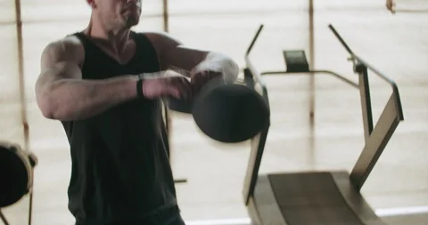 Training with kettlebells, intense strength exercise in closed gym. Men doing Stock-Footage 129979230