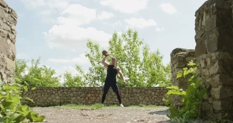 Training with kettlebells, intense strength exercise outdoor. Men doing workout Stock Footage 132974343