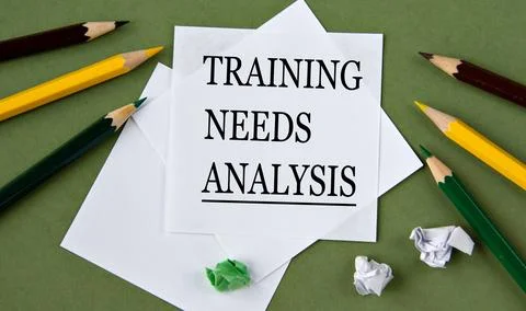 TRAINING NEEDS ANALYSIS - words on white paper on a green background with pen Stock Photos