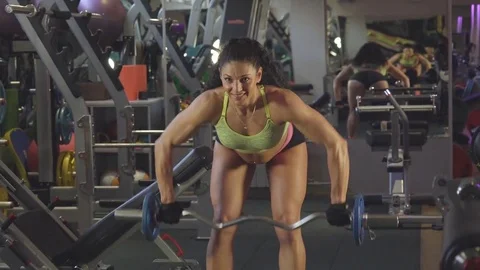Training over the bar, she raises her hands bent barbell to the chest Stock Footage 70383095