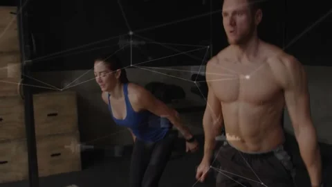 Training pair exhaling rising from squat and jumping for fitness in gym while Stock Footage 330540614