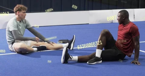 Training partners starting warmup doing hamstring stretches on blue court with Video stock 320484958