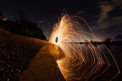 Trajectory of burning sparks reflected on the river surface Foto stock