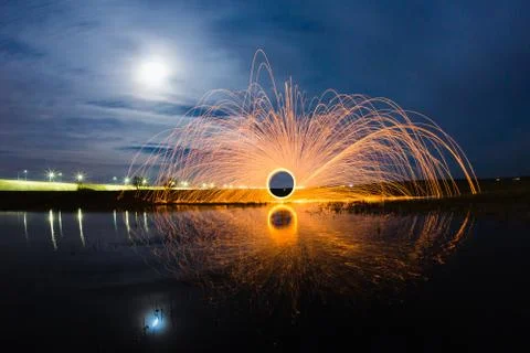 Trajectory of burning sparks reflected on the river surface Stock Photos