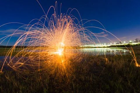 Trajectory of burning sparks reflected on the river surface Foto stock