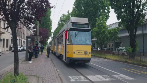 Tram arriving at stop as passengers board in Milan Stock Footage 339244335