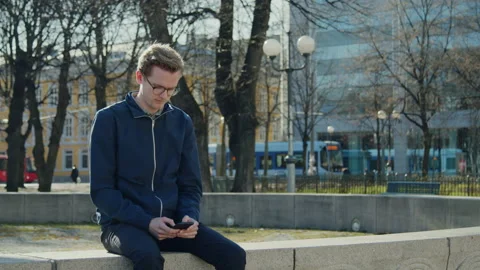 Tram going by in the background while a young man navigate his way by phone Stock Footage 135418594