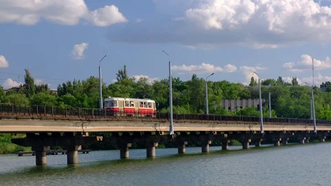 Tram moves along the bridge over the river in a city Stock Footage 112977039