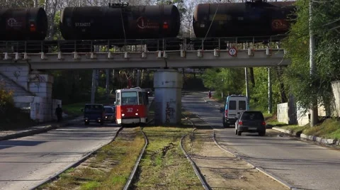Tram passes under the bridge on which there is a freight train. Video stock 64381061
