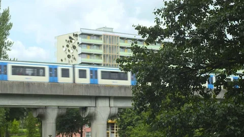 Tram Passing By On A Cloudy Day With Lots Of Green, A Building And A Bridge Stock Footage 126700999