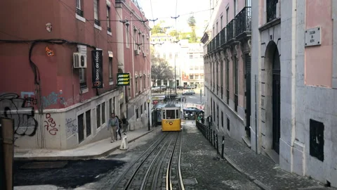 Tram Passing on Narrow Down Hill Street in Lisbon Portugal Stock Footage 139453520