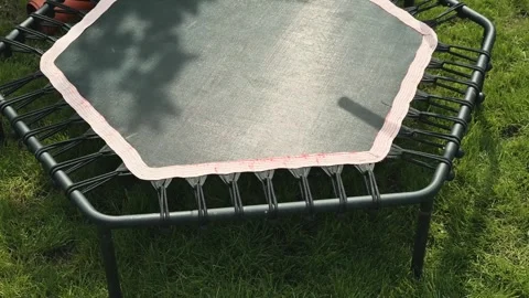 A trampoline is placed in a backyard, showcasing the hexagonal mat and sturdy Stock Footage 338447855