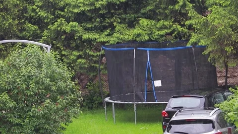 Trampoline standing in the backyard, in the a green garden in the rain Vídeos de archivo 329063875