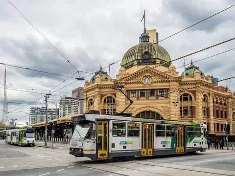 Trams moving at the front of the iconic Flinders Street Station Stock Photos