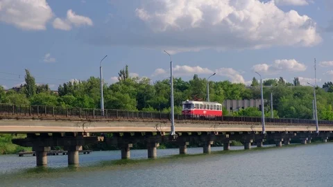 Tramway moves along the bridge over the river in a city 스톡 동영상 112977059