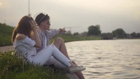 Trandy couple talking by the river. Holidays, vacation, love and people concept  Stock Footage 130512943