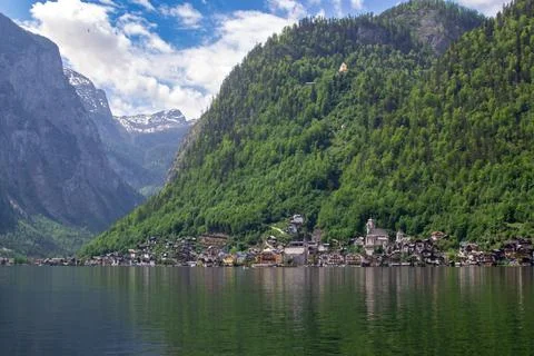 A tranquil alpine lake against the backdrop of mountains with green forest Stock Photos