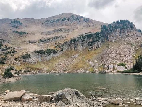 Tranquil alpine lake at the base of a rugged mountain Stock-Fotos