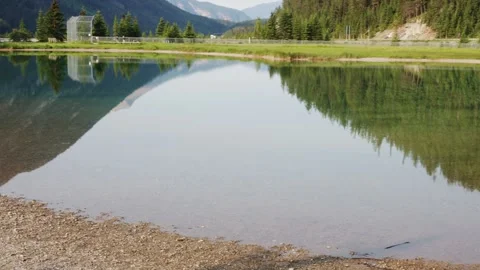 Tranquil Alpine Lake with Reflective Mountain Scenery and Trees Stock Footage 255967778