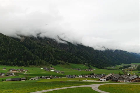 Tranquil Alpine village with green fields and misty mountains is a peaceful Stock Footage 280110146