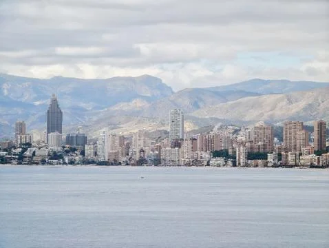 Tranquil Bay Under Cloudy Sky, Peaceful Harbor With Mountain Backdrop And Stock Photos