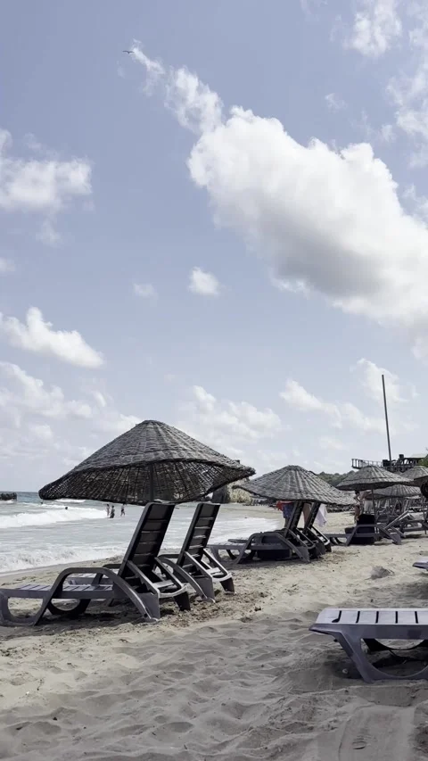 A tranquil beach scene featuring lounge chairs and umbrellas on golden sand.. Stock Footage 307302840