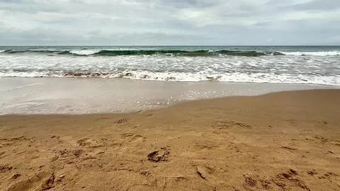 A tranquil beach scene with rolling waves crashing on the shore and a sooth.. Stock Photos
