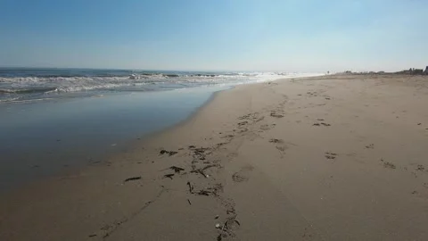 Tranquil beach scene with soft waves lapping the sandy shore under a clear blue Stock Footage 293889530