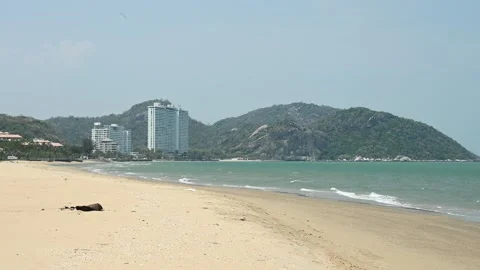 Tranquil beach view with distant buildings and calm waves Видео 323320962