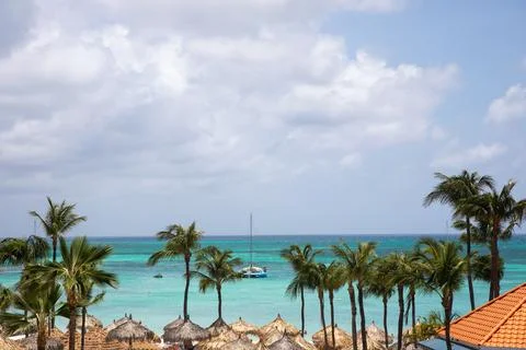 Tranquil beach view with palm trees and a sailboat near the shore in tropical Foto stock