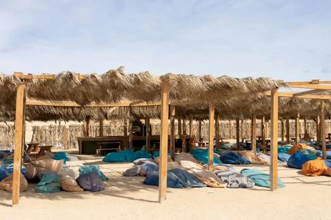 Tranquil beachside oasis with straw canopy and colorful bean bags for relaxation 스톡 사진