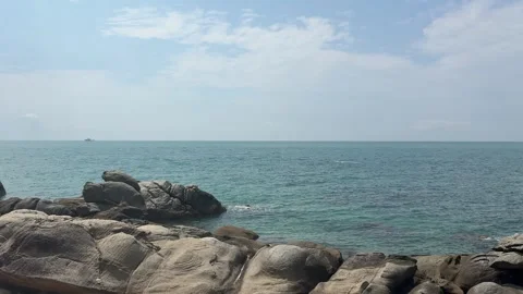 Tranquil Blue Ocean and Weathered Rocks on Tropical Coastline Stock Footage 330865555