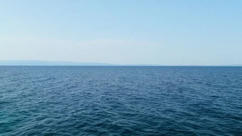 The tranquil blue sea with gentle waves and a clear horizon under a bright sky Stock Footage 346677735