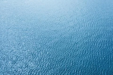 Tranquil blue water surface reflecting sunlight against soft ripples Foto stock